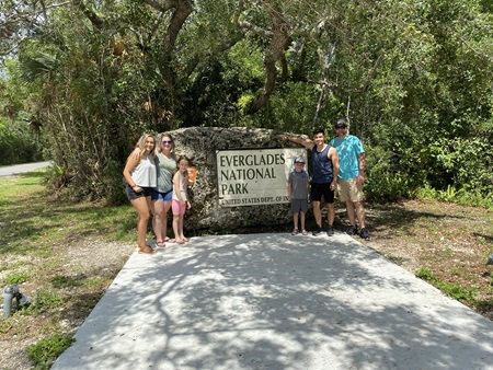 La familia posa frente a un letrero del Parque Nacional