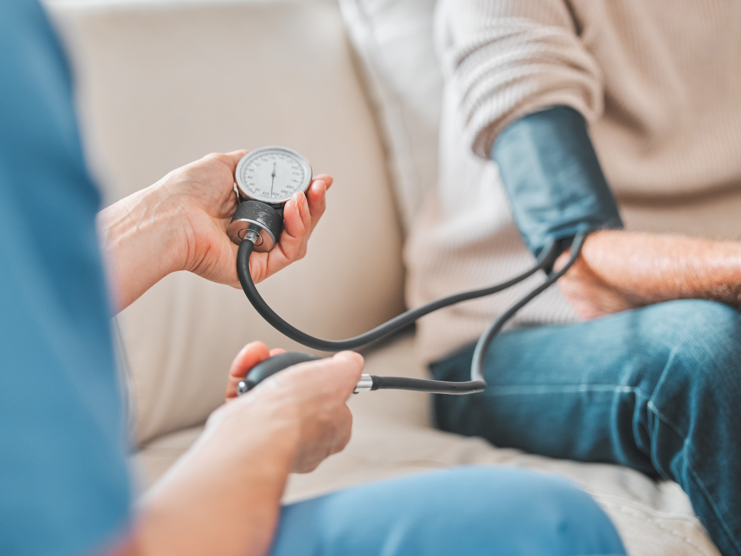 Healthcare provider monitoring patient's blood pressure using arm cuff.
