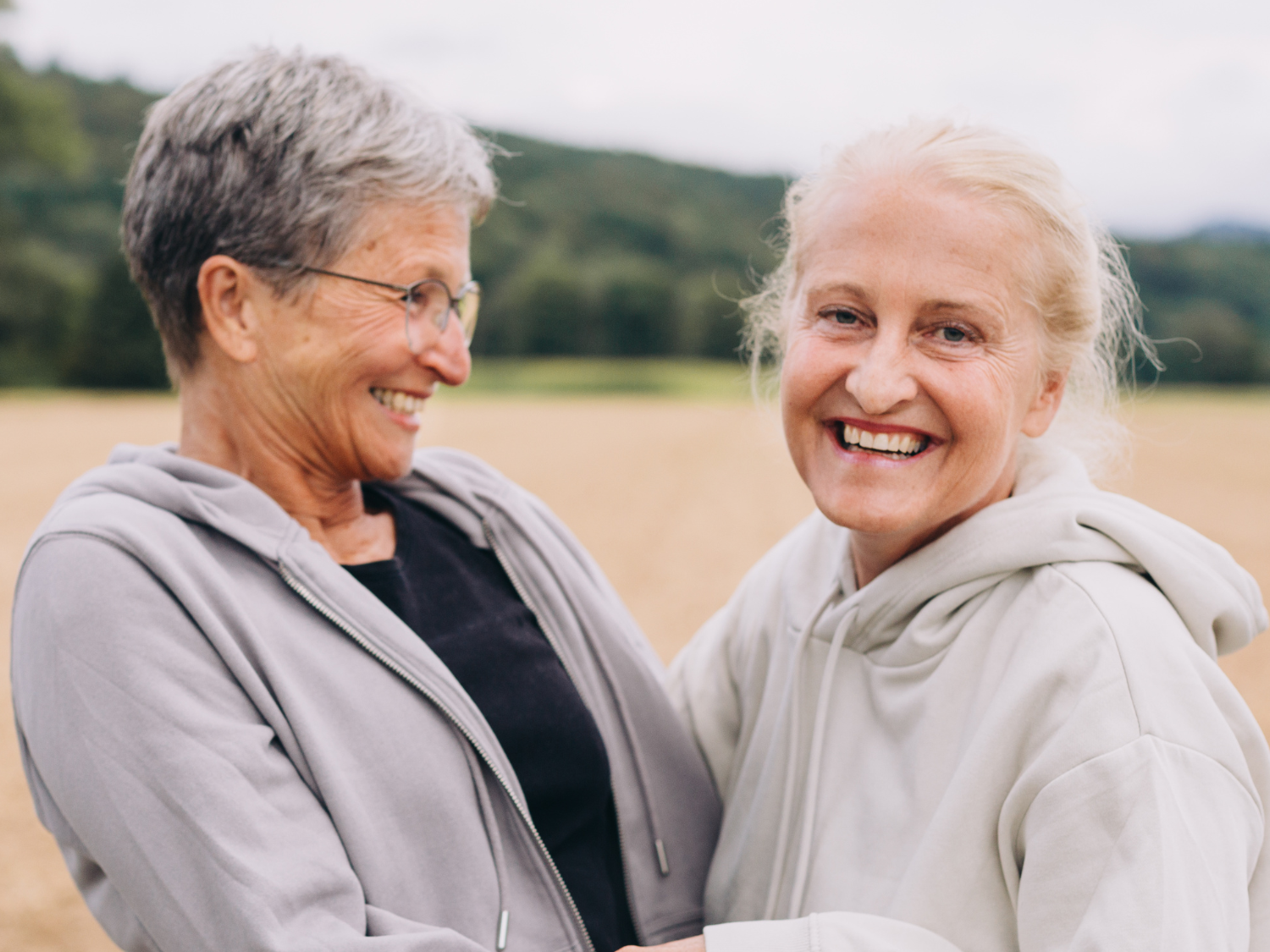 Dos mujeres mayores sonriendo unas a otras en un campo