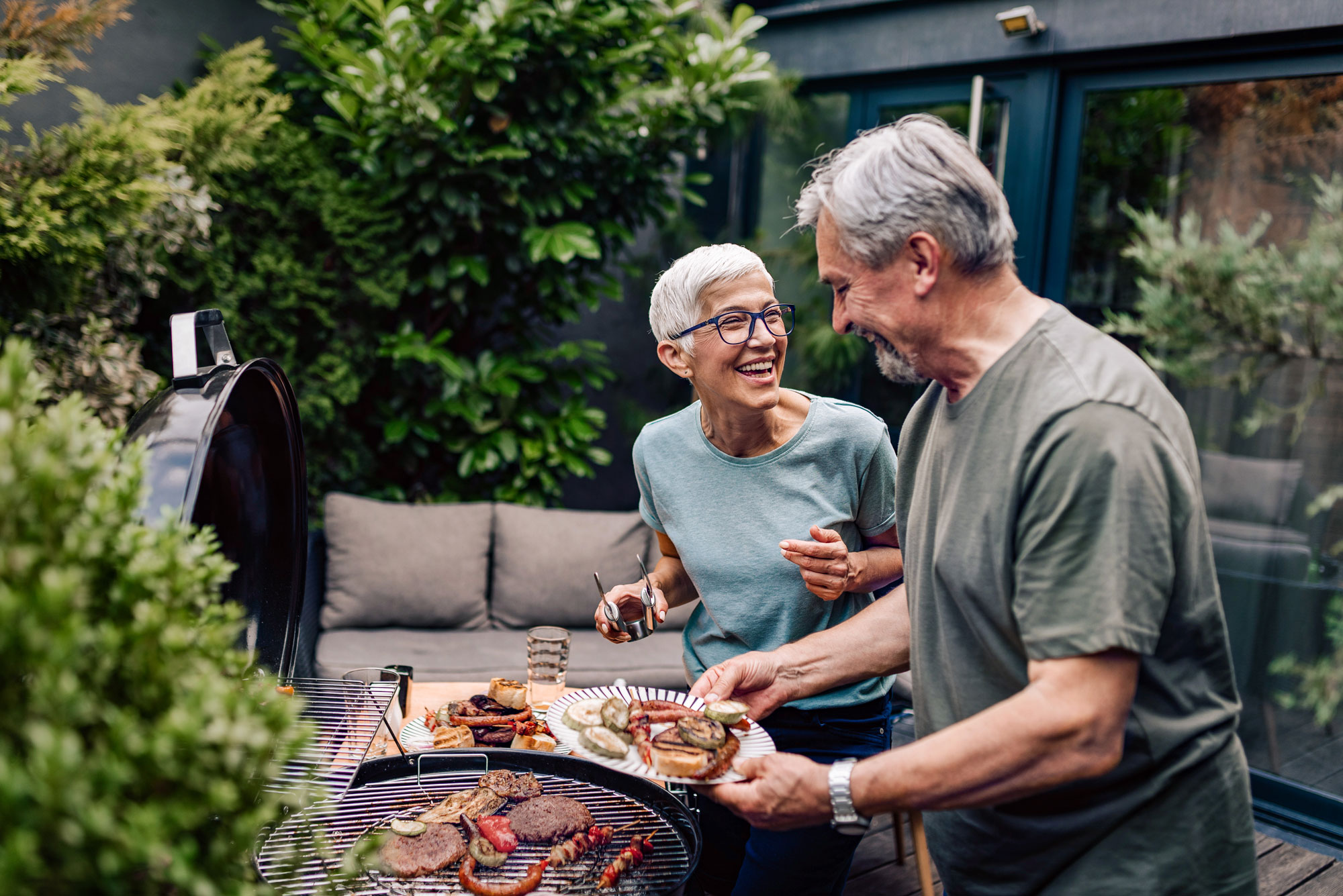 Pareja anciana cocinando juntos al aire libre