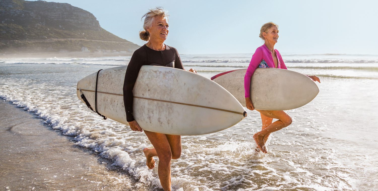 two women running with surf boards