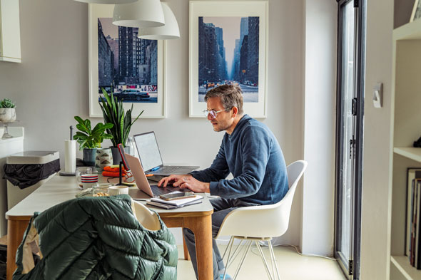 A man sitting at his desk, working on his laptop.