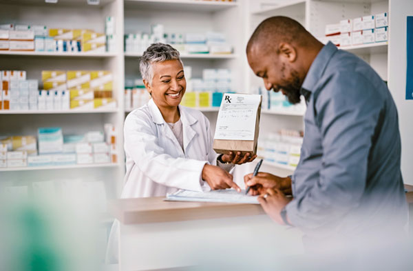 A pharmacist handing a man his prescription