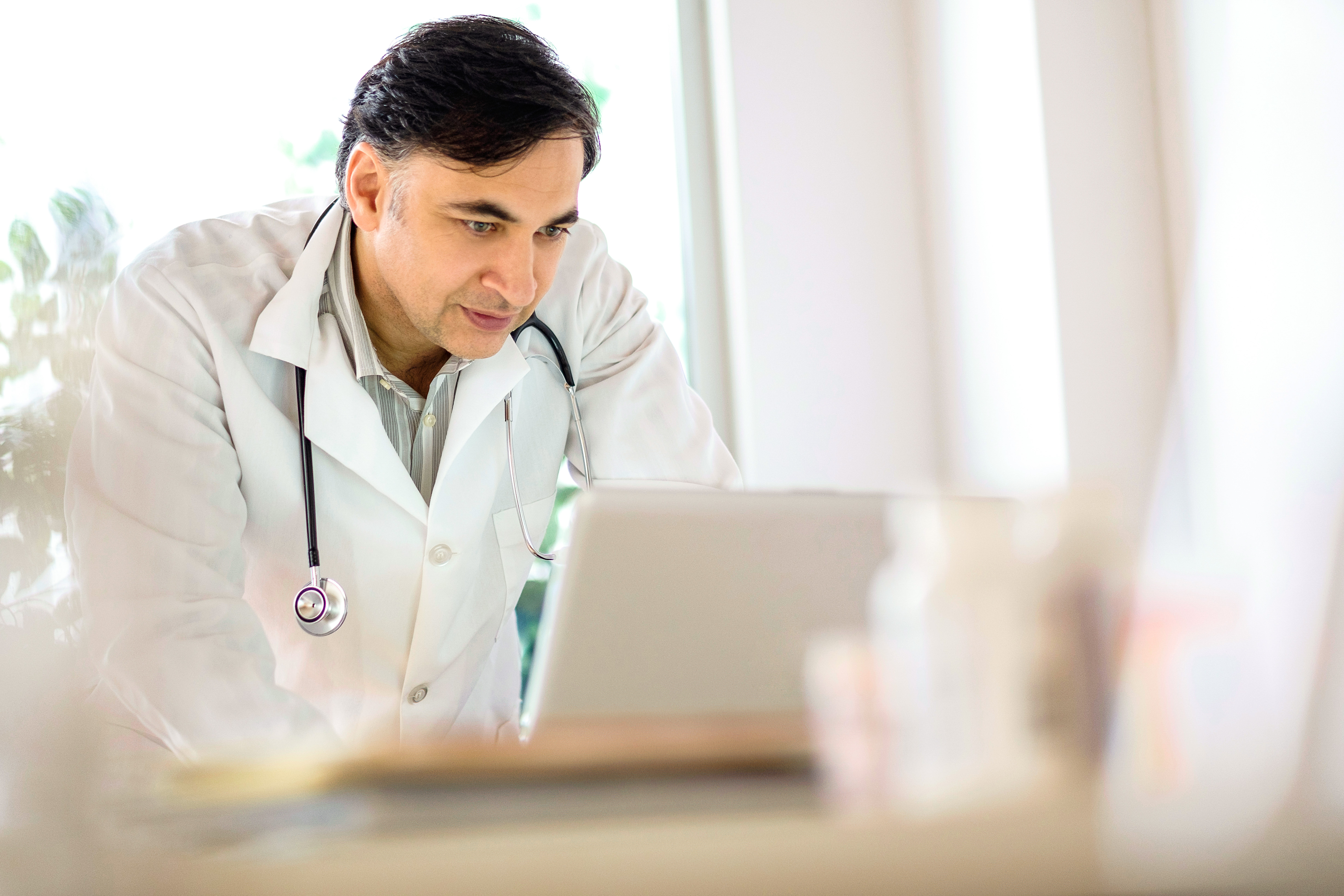 Male doctor reading on a laptop